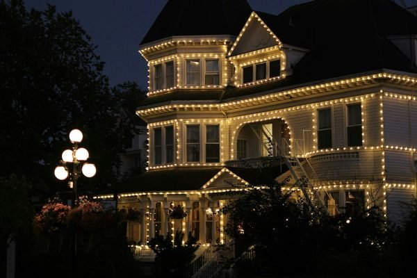 A full property professionally lit with warm white Christmas lights at dusk