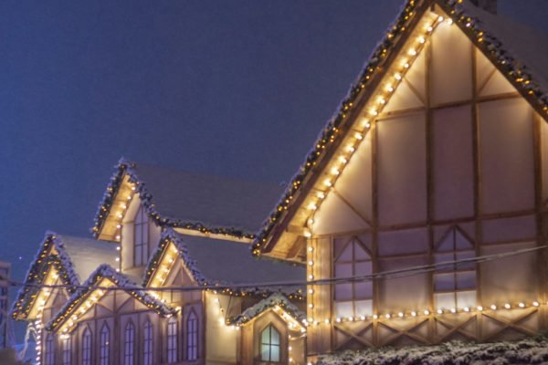 Warm white Christmas lights outlining the rooflines and gutters of houses at dusk